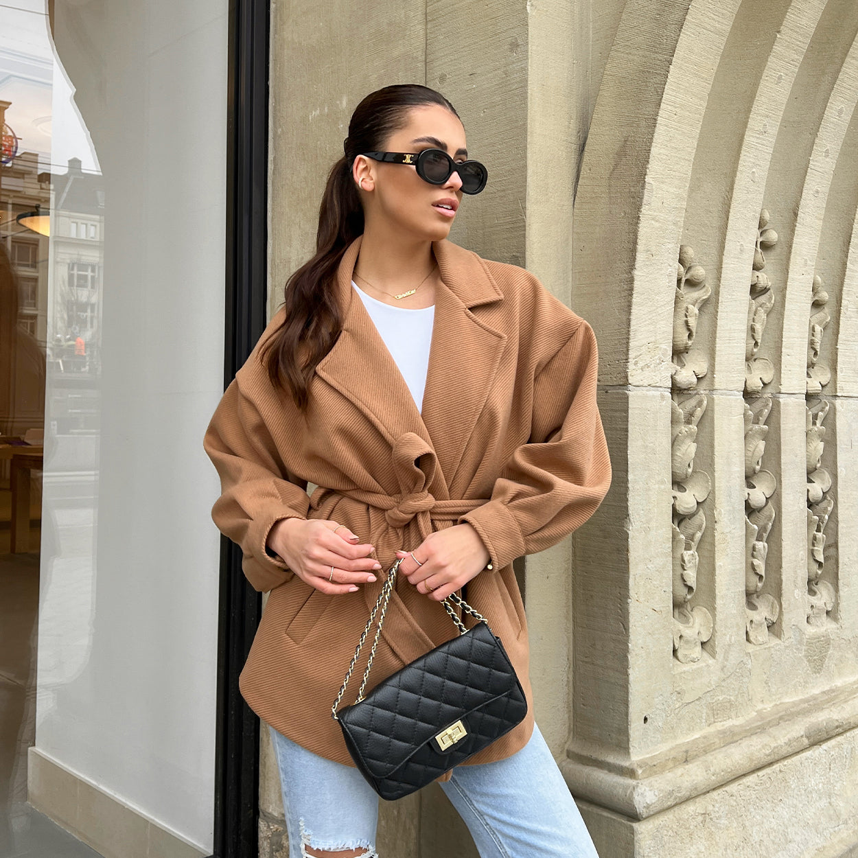 KLEDING-CAMEL-KORTE-TRENCH-LANGE-MOUWEN-STRIK-SHORT-WITTE-BASIC-KORTE-MOUWEN-TSHIRT-BLAUWE-DENIM-JEANS-SPIJKERBROEK-ZWARTE-LEREN-TAS-GOUDEN-DETAILS-GOUDEN-KETTING-SIERADEN-ZWARTE-ZONN